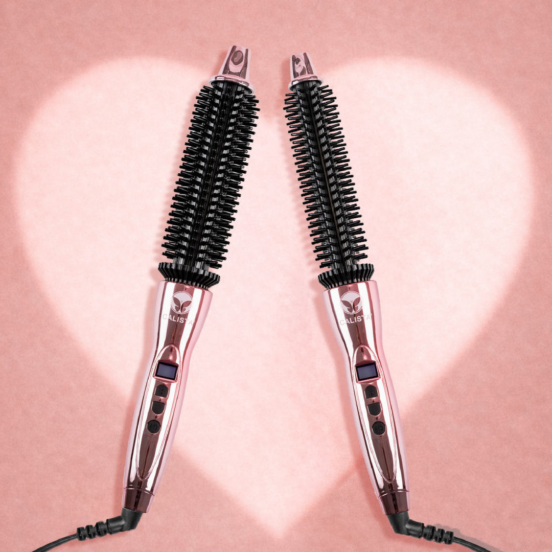 Two pink Calista Tools Perfecter Pro Bestseller Duo brushes with black bristles stand upright, facing each other against a pink background with a glowing white heart—showcasing this stylish ceramic ionic hair styling tool.