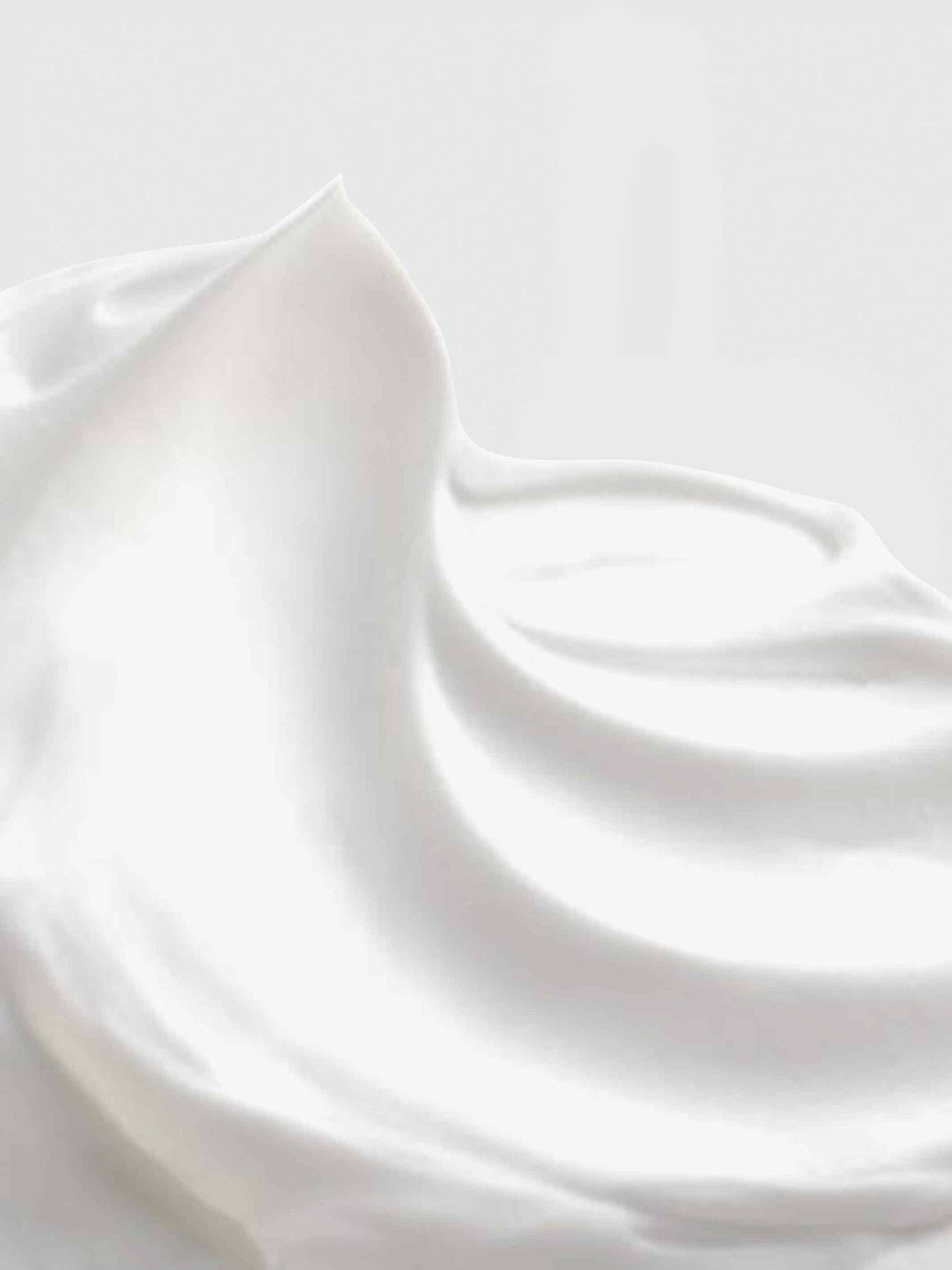 Close-up of Calista Tools STRATOSPHERE Bounce Cream, featuring smooth, white cream with soft peaks and gentle swirls that highlight its voluminizing effect against a light background.
