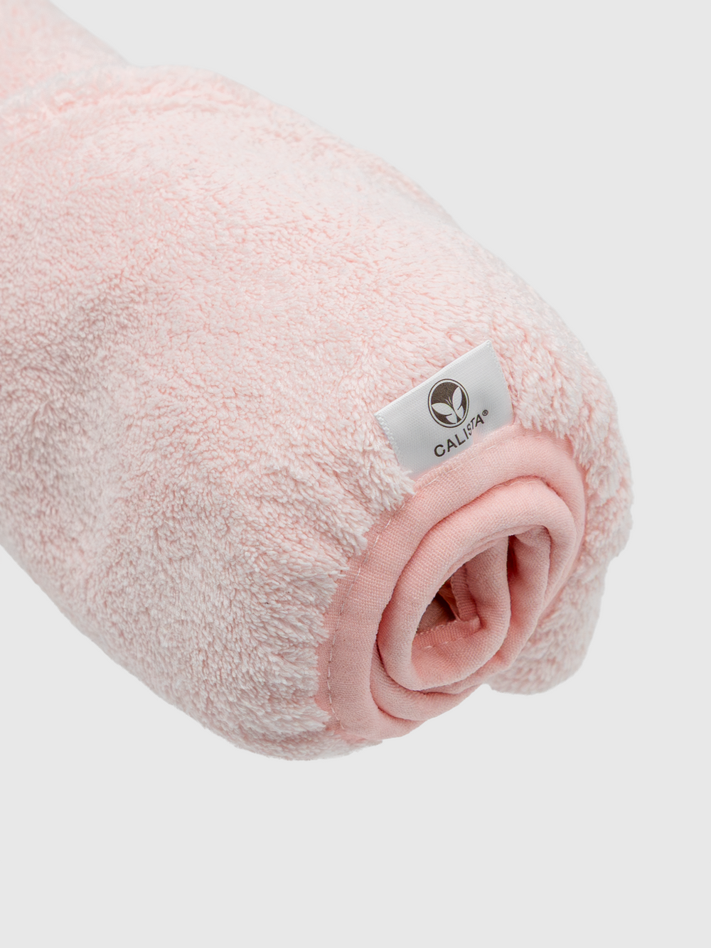 A rolled-up, light pink Duet Satin-Microfiber Twist Towel by Calista Tools with a white logo tag reading CALIFA, displayed on a plain white background.