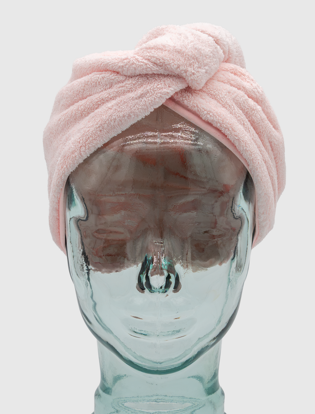 A clear glass mannequin head displays the Calista Tools Duet Satin-Microfiber Twist Towel in light pink, set against a plain white background.
