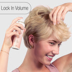 A woman with short blonde hair holds a can of embellish finishing spray against her hair, with the text 'Lock In Volume' in the top left corner.