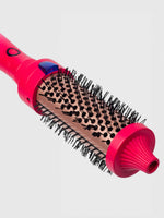 A close-up of the Calista Tools Vault FAUXblo Thermal Blowout Brush 1.77" shows its pink and black design, densely packed bristles, power button, and vented barrel for effortless styling, drying, and volumizing.
