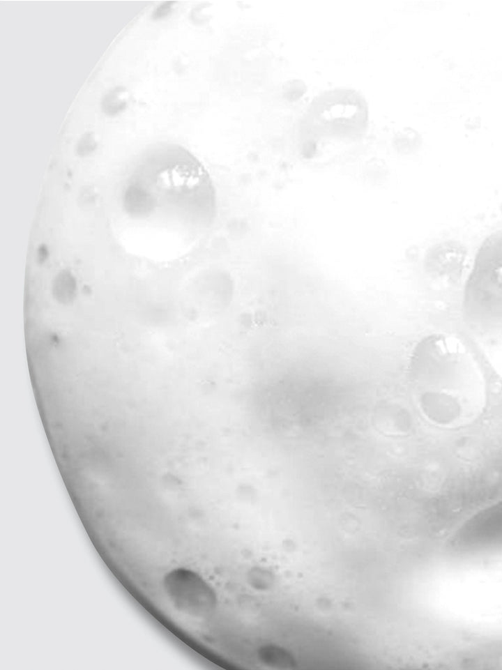 Close-up of white, foamy bubbles clustered together, resembling soap lather or foam on a smooth surface, with various sizes of bubbles creating a textured appearance.