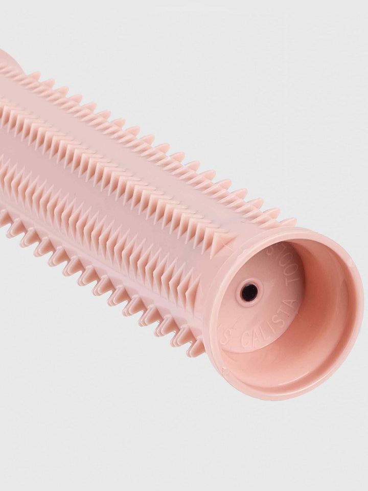 A close-up of a pink cylindrical hair styling roller with rows of short, evenly spaced plastic bristles and a hollow center, designed for curling or volumizing hair.