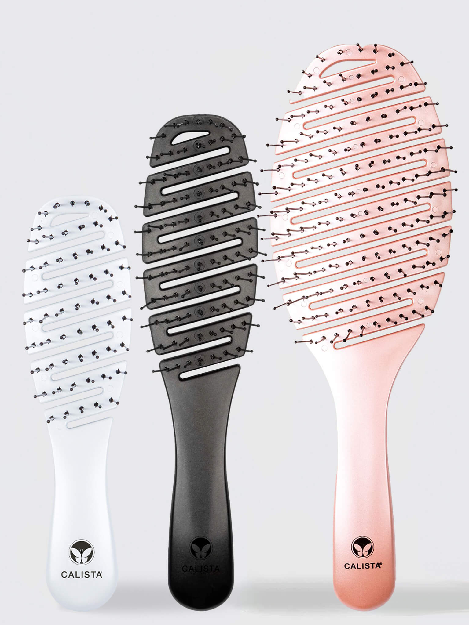 Three SMOOTHIE Brush Trio hairbrushes by Calista Tools in white, black, and rose gold stand upright. Each features a curved, vented design and the Calista logo on the handle for easy detangling and effortless hair styling. 