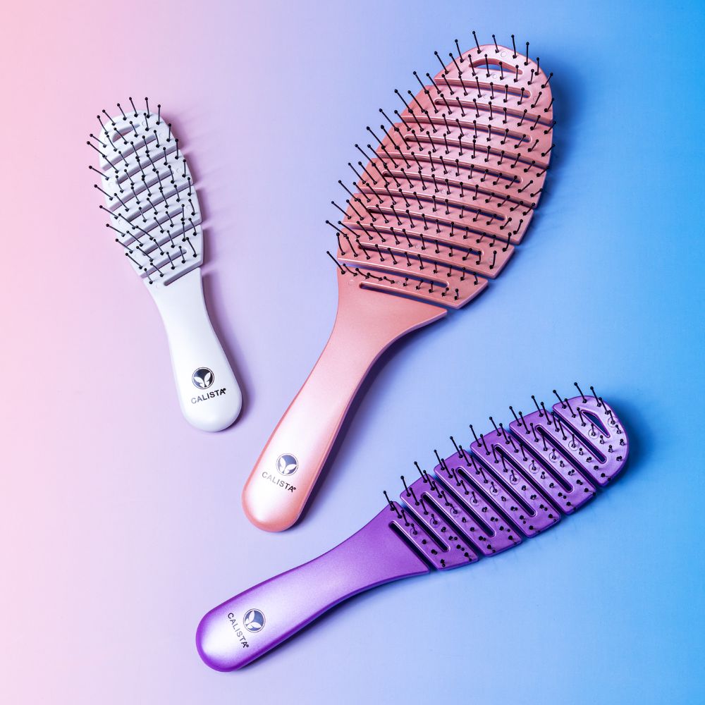 The Calista Tools SMOOTHIE Brush Trio includes three detangling brushes in white, pink, and purple with black-tipped bristles and branded handles—ideal for easy detangling and styling, showcased on a blue and pink gradient background.